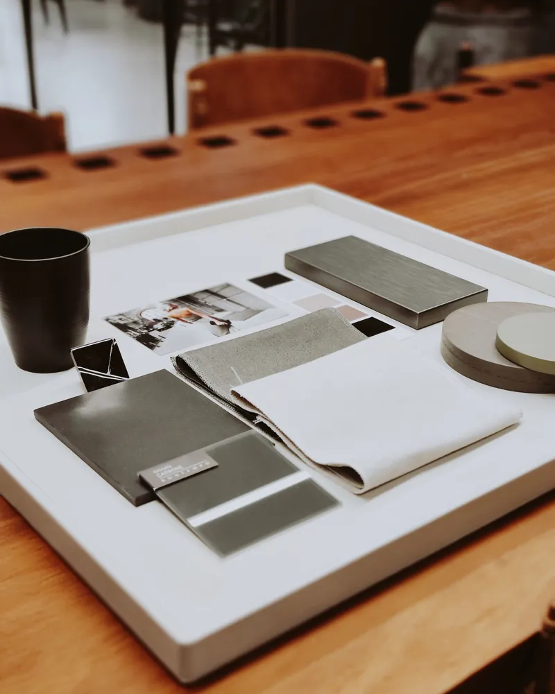 Neutral fabric and material samples on a tray on a timber desk