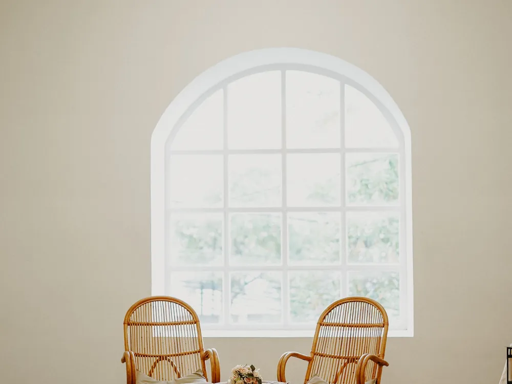 Bright room with an arched window and a pair of rattan chairs